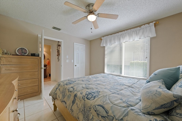 bedroom with ceiling fan, light tile patterned floors, and a textured ceiling