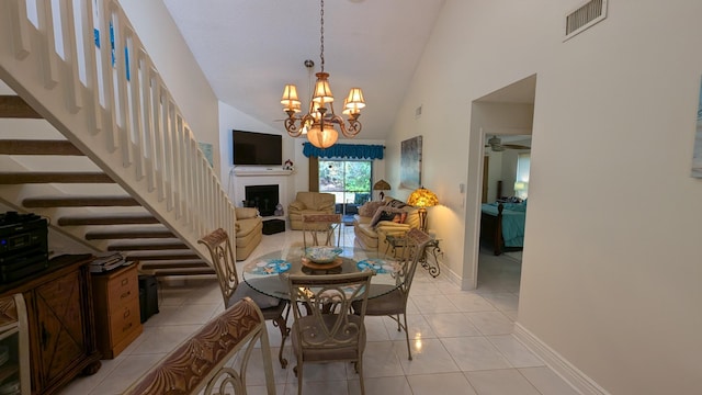 tiled dining room with ceiling fan with notable chandelier and high vaulted ceiling