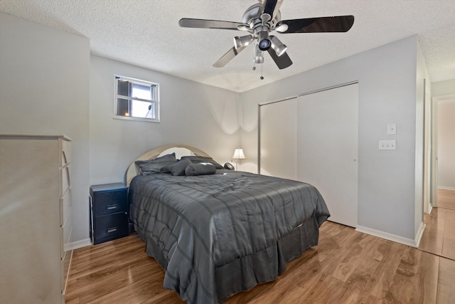 bedroom featuring ceiling fan, a closet, a textured ceiling, and light hardwood / wood-style flooring