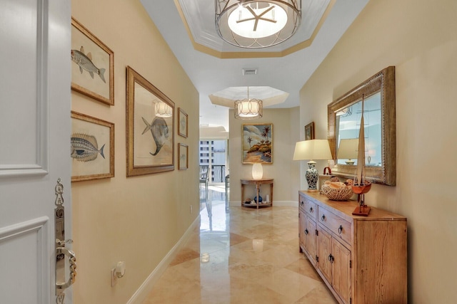 hallway featuring a wealth of natural light, crown molding, and a raised ceiling