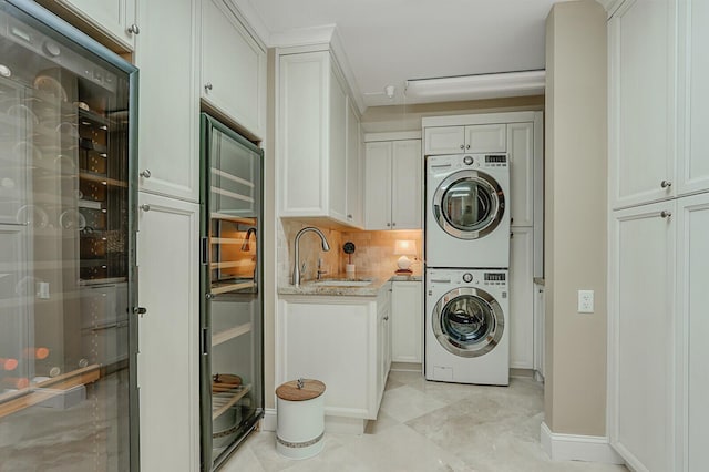 laundry area featuring sink, stacked washing maching and dryer, ornamental molding, and wine cooler