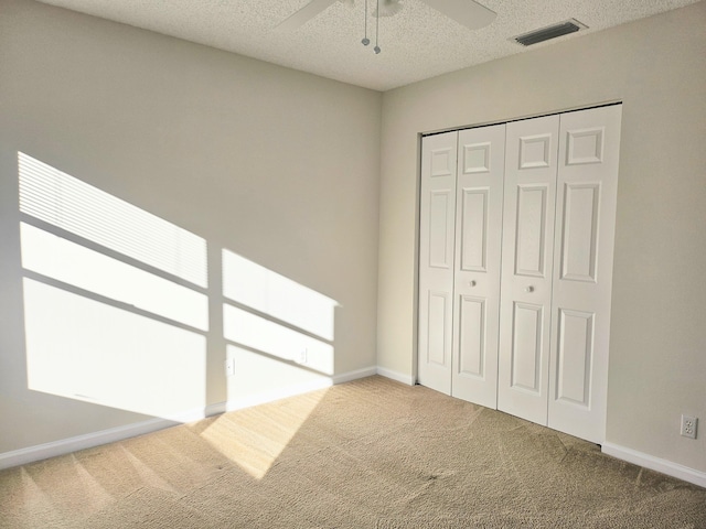 unfurnished bedroom featuring carpet, ceiling fan, a textured ceiling, and a closet