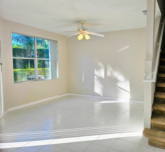 unfurnished room with a textured ceiling, ceiling fan, and light tile patterned flooring