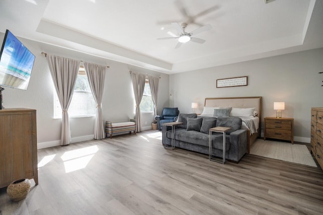 bedroom with a raised ceiling, ceiling fan, and wood-type flooring