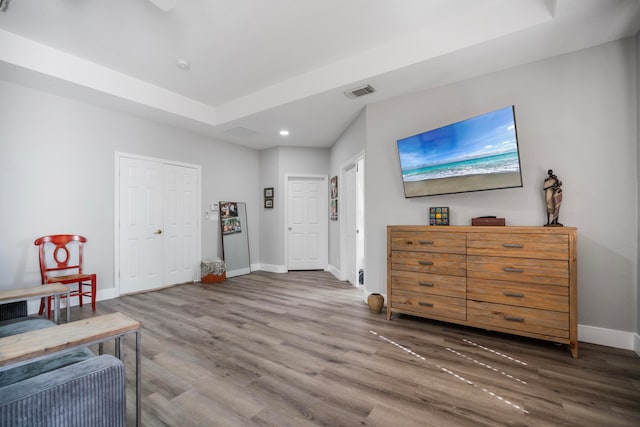 living area with hardwood / wood-style flooring and a raised ceiling