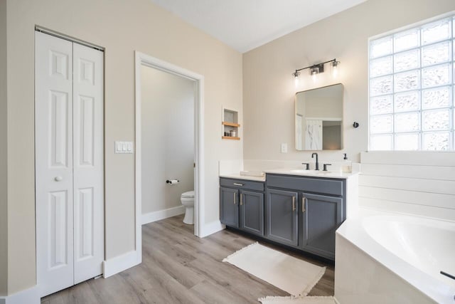 bathroom with hardwood / wood-style flooring, vanity, toilet, and a wealth of natural light