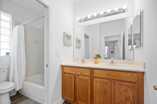 full bathroom featuring hardwood / wood-style floors, vanity, shower / bath combination with curtain, and toilet