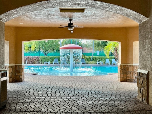 view of swimming pool with pool water feature and ceiling fan