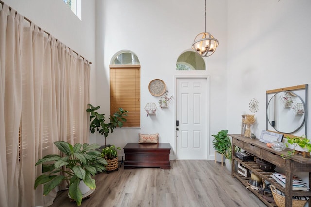 entrance foyer featuring light hardwood / wood-style flooring, a high ceiling, and an inviting chandelier