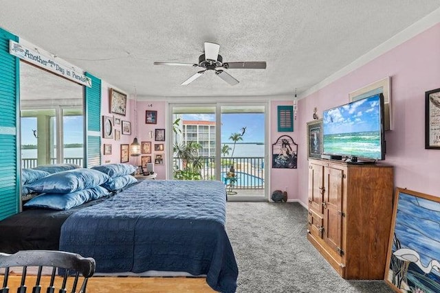 carpeted bedroom featuring ceiling fan, a water view, a textured ceiling, and access to outside