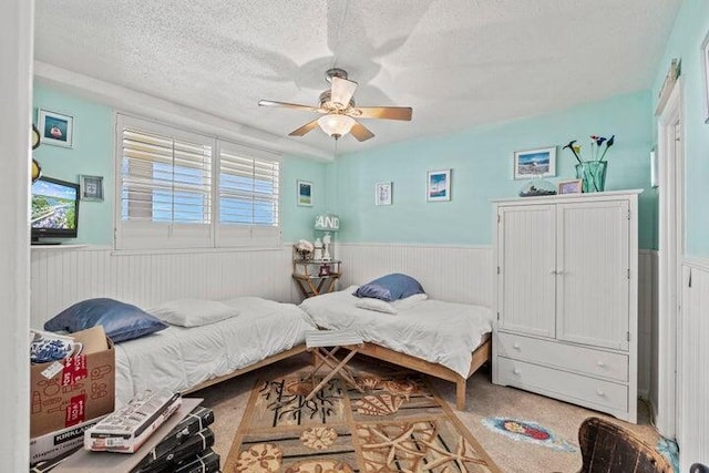 bedroom with carpet flooring, ceiling fan, and a textured ceiling