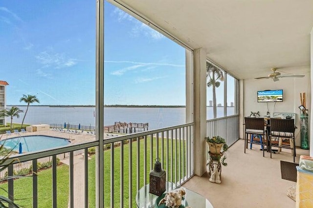 sunroom / solarium featuring a water view and ceiling fan