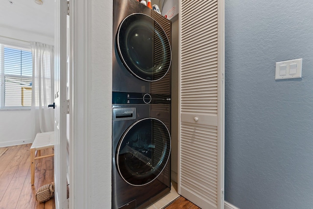 laundry room featuring wood-type flooring and stacked washer and clothes dryer