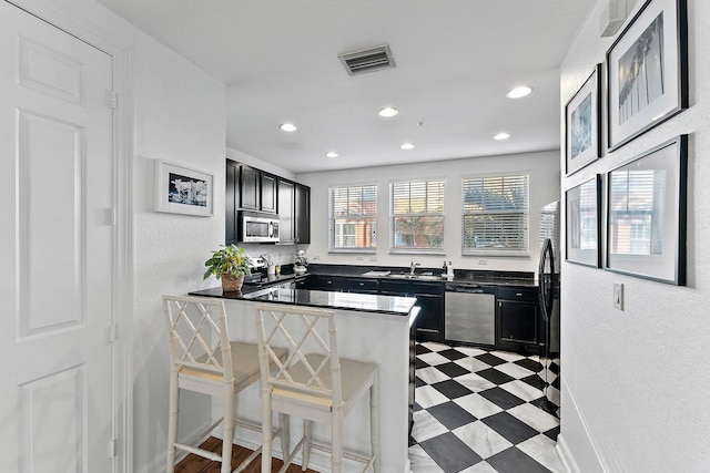 kitchen featuring a breakfast bar area, kitchen peninsula, sink, and stainless steel appliances