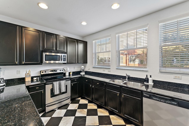 kitchen featuring appliances with stainless steel finishes, plenty of natural light, dark stone counters, and sink