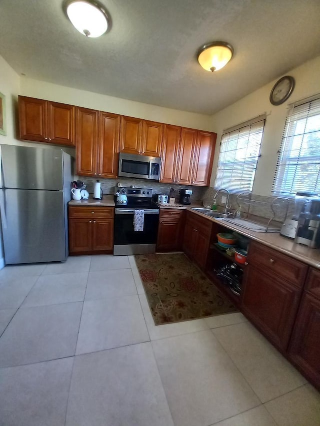 kitchen with light tile patterned floors, backsplash, stainless steel appliances, and sink