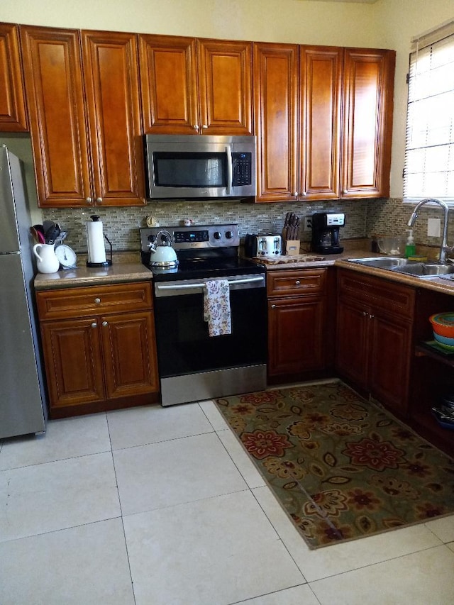 kitchen featuring backsplash, light tile patterned floors, sink, and appliances with stainless steel finishes