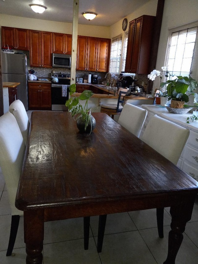 dining space with a healthy amount of sunlight, light tile patterned flooring, and sink