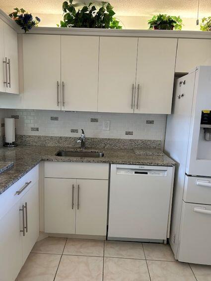 kitchen with white cabinetry, white appliances, sink, and dark stone counters