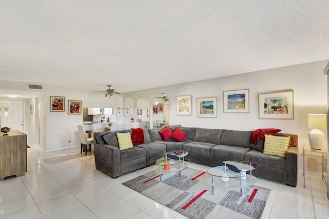 tiled living room with a textured ceiling and ceiling fan