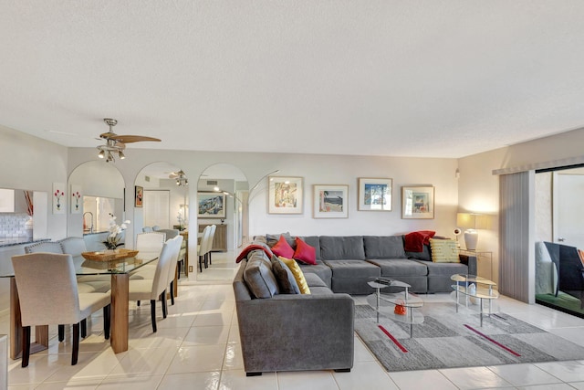 living room with a textured ceiling, ceiling fan, light tile patterned floors, and sink