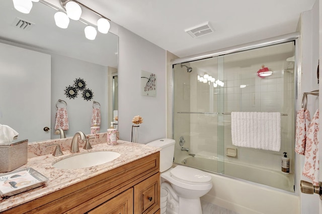 full bathroom featuring vanity, toilet, and shower / bath combination with glass door