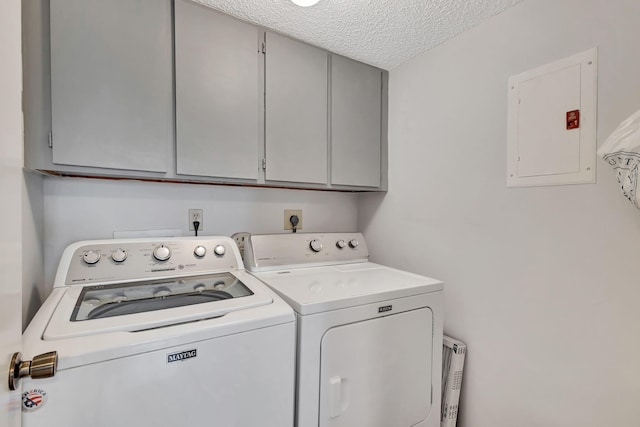 laundry area featuring cabinets, a textured ceiling, electric panel, and washing machine and clothes dryer