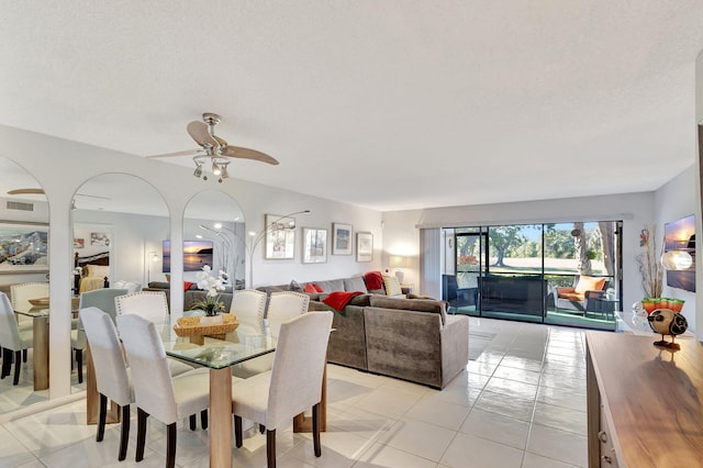 tiled dining space with a textured ceiling and ceiling fan