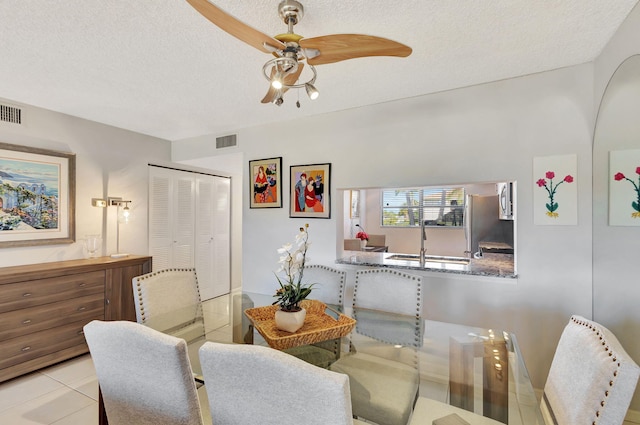 tiled dining room with ceiling fan and a textured ceiling