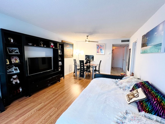 bedroom featuring ceiling fan, hardwood / wood-style floors, and a textured ceiling