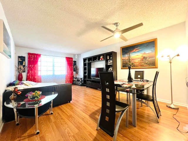 dining area featuring ceiling fan, wood-type flooring, and a textured ceiling