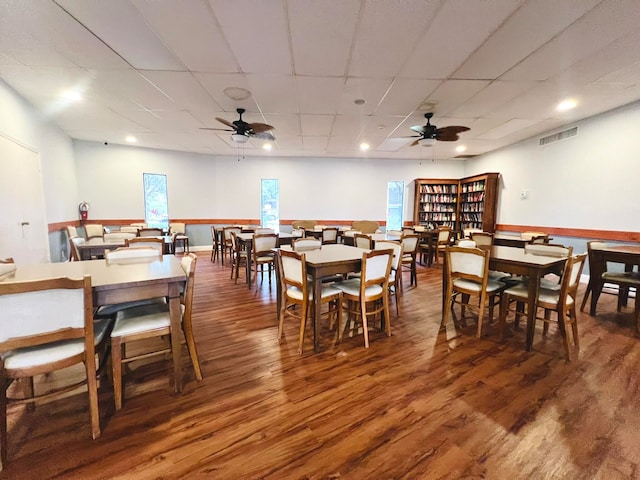 dining space featuring ceiling fan, a drop ceiling, and dark wood-type flooring