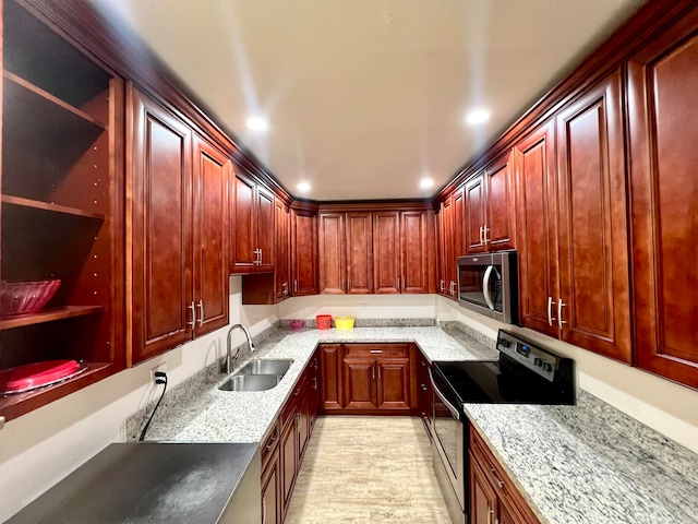 kitchen featuring light stone countertops, appliances with stainless steel finishes, light hardwood / wood-style floors, and sink