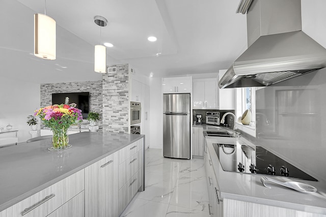 kitchen with white cabinetry, sink, hanging light fixtures, stainless steel appliances, and ventilation hood