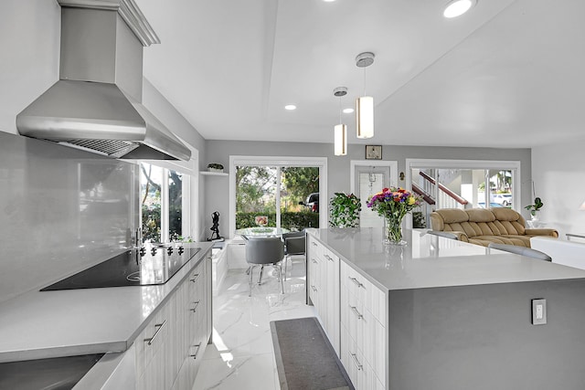 kitchen with white cabinets, a healthy amount of sunlight, wall chimney exhaust hood, and a large island