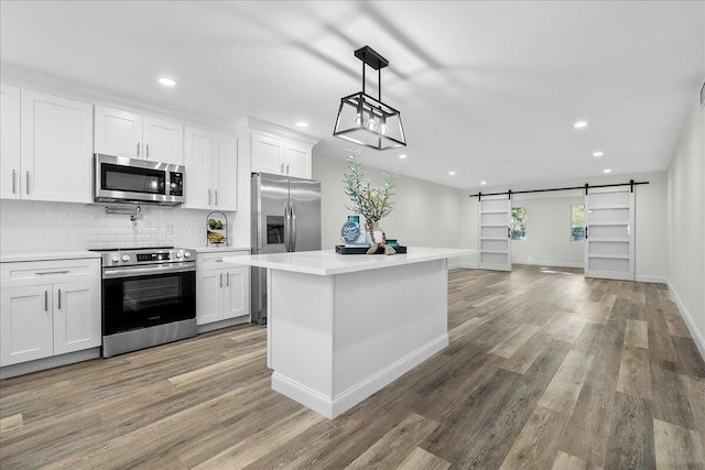 kitchen with a barn door, white cabinetry, and appliances with stainless steel finishes