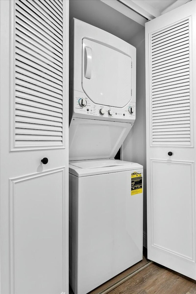 laundry room featuring dark hardwood / wood-style floors and stacked washer / dryer