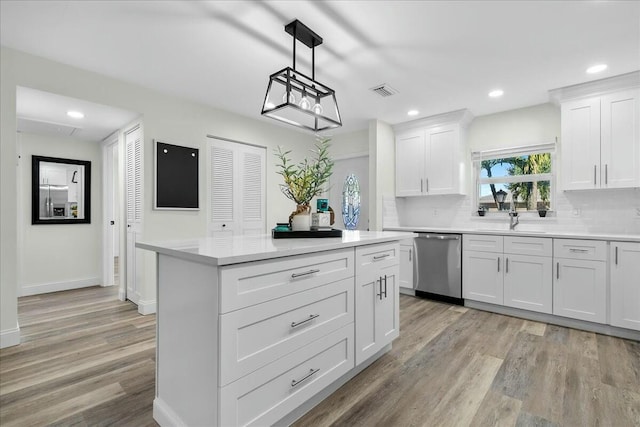 kitchen with white cabinets, light wood-type flooring, stainless steel dishwasher, and sink