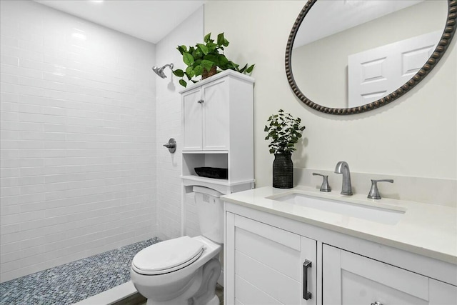 bathroom featuring vanity, toilet, and a tile shower