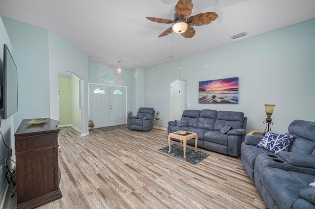 living room featuring ceiling fan, light hardwood / wood-style floors, and a textured ceiling