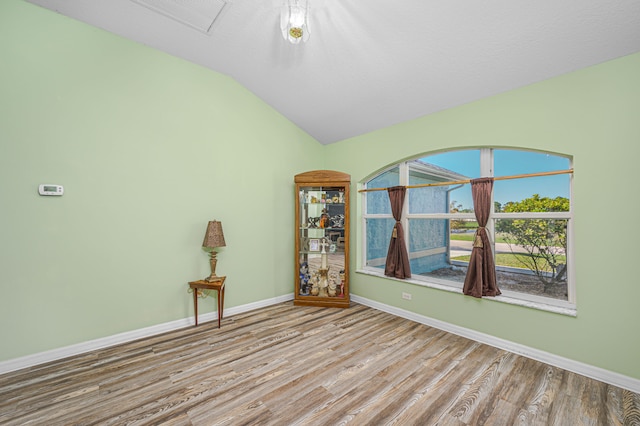 unfurnished room with light wood-type flooring and lofted ceiling