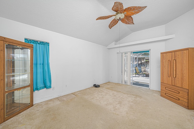 carpeted spare room with a textured ceiling, ceiling fan, and lofted ceiling