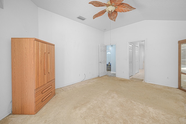 unfurnished bedroom featuring light carpet, ensuite bathroom, vaulted ceiling, ceiling fan, and a textured ceiling