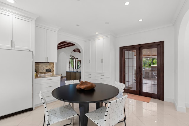 tiled dining space featuring french doors and crown molding