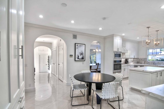 tiled dining area featuring an inviting chandelier, crown molding, and sink