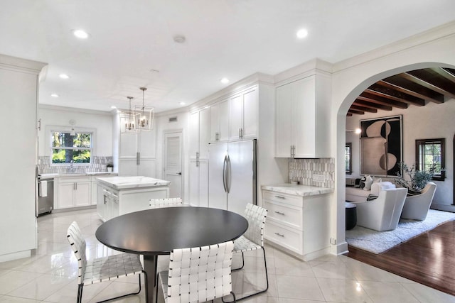 kitchen with hanging light fixtures, stainless steel appliances, beamed ceiling, backsplash, and a kitchen island