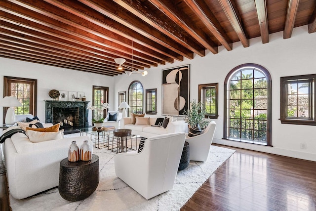 living room with beam ceiling, a premium fireplace, a wealth of natural light, and wood-type flooring