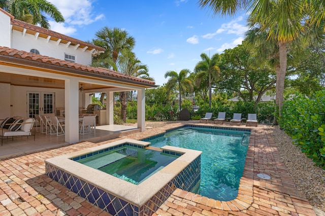 view of swimming pool with an in ground hot tub, a patio, and an outdoor kitchen