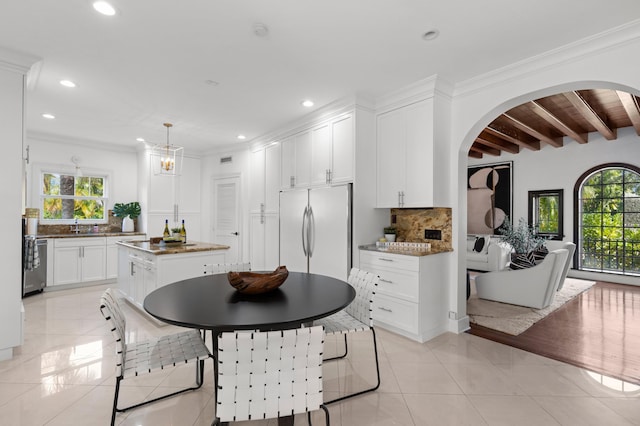 dining area featuring light tile patterned flooring, beamed ceiling, a healthy amount of sunlight, and ornamental molding