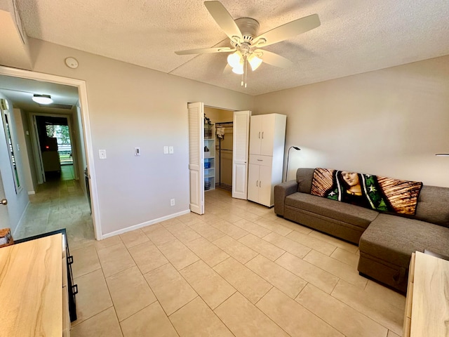 living room featuring ceiling fan, light tile patterned floors, and a textured ceiling